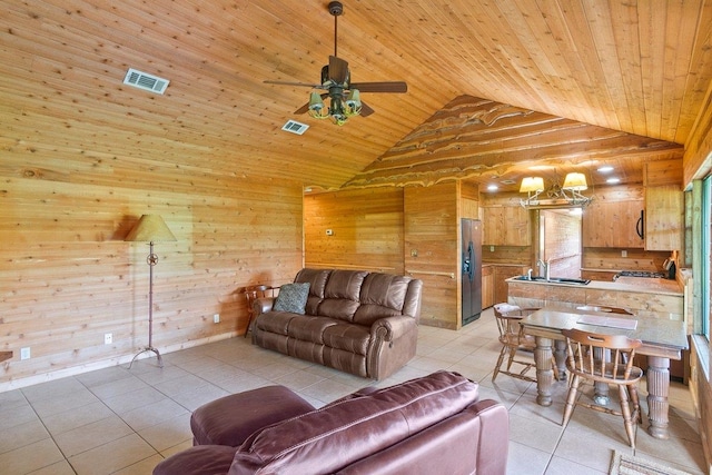 tiled living room with wood ceiling, ceiling fan, wooden walls, sink, and high vaulted ceiling