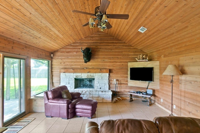 tiled living room with ceiling fan, wood walls, a stone fireplace, and wood ceiling