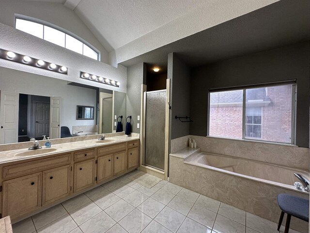 full bathroom with double vanity, vaulted ceiling, a stall shower, a sink, and tile patterned floors