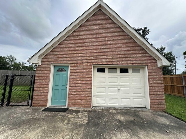 garage featuring concrete driveway and fence