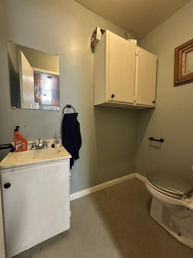 bathroom with baseboards, vanity, toilet, and concrete floors