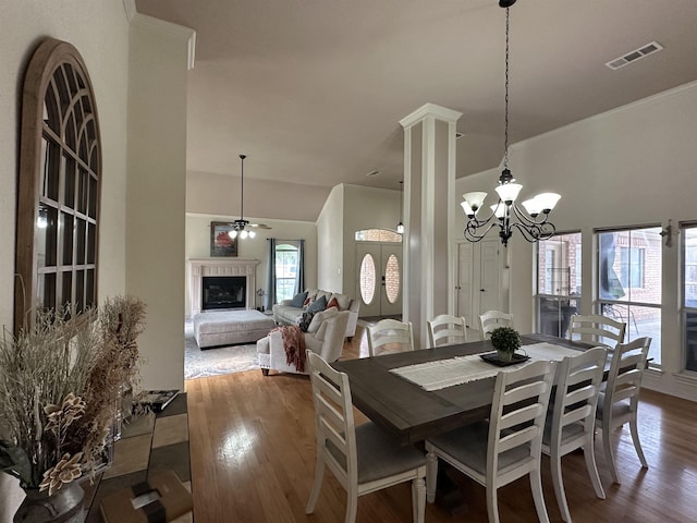 dining area with visible vents, ceiling fan with notable chandelier, wood finished floors, and a fireplace