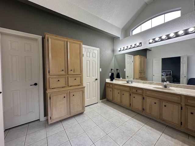 bathroom featuring double vanity, vaulted ceiling, a sink, and tile patterned flooring