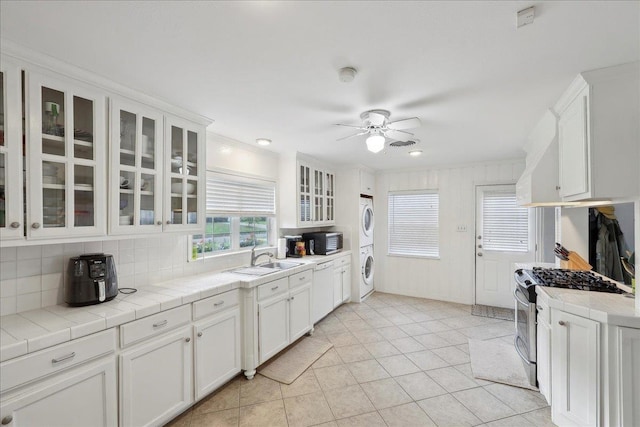 980 N 23rd St, Beaumont, TX 77706 - kitchen featuring stainless steel appliances, estacked washer and dryer, a sink, and tile countertops