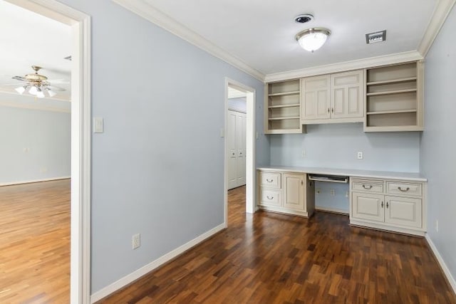 unfurnished office with dark hardwood / wood-style flooring, crown molding, built in desk, and ceiling fan