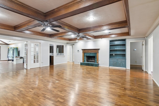 unfurnished living room with hardwood / wood-style flooring, ceiling fan, a high end fireplace, and beamed ceiling