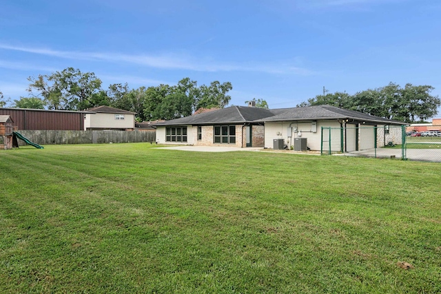 back of house featuring cooling unit, a lawn, and a playground