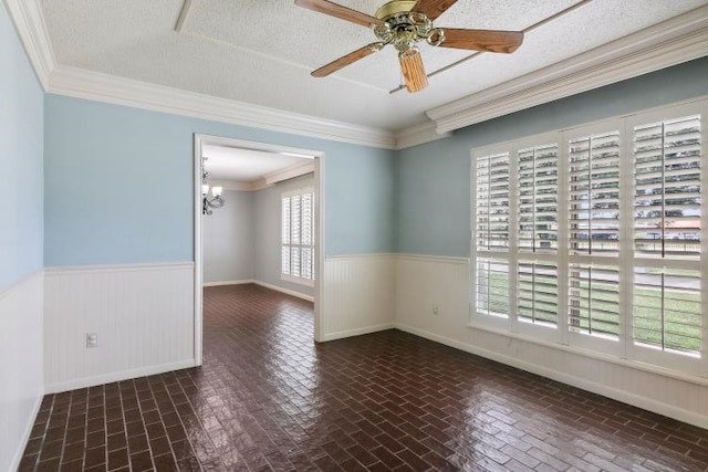 spare room featuring crown molding, ceiling fan with notable chandelier, and a textured ceiling