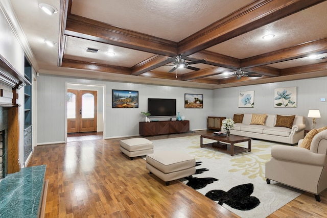 living room with french doors, coffered ceiling, light wood-type flooring, ornamental molding, and beam ceiling