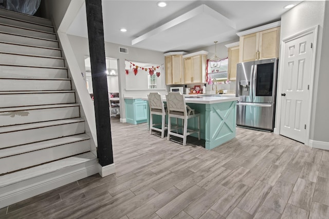 kitchen with a center island, pendant lighting, stainless steel refrigerator with ice dispenser, light hardwood / wood-style flooring, and a kitchen breakfast bar