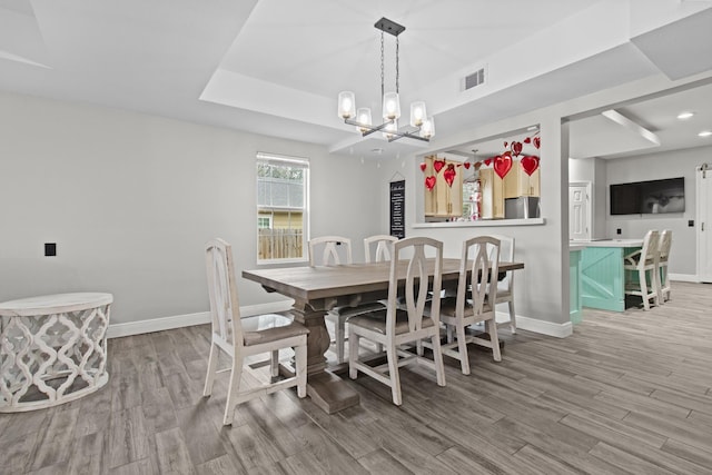 dining space with hardwood / wood-style floors, a tray ceiling, and a notable chandelier