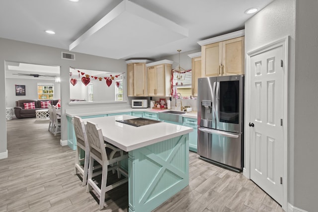 kitchen with pendant lighting, a kitchen island, stainless steel refrigerator with ice dispenser, sink, and a kitchen breakfast bar