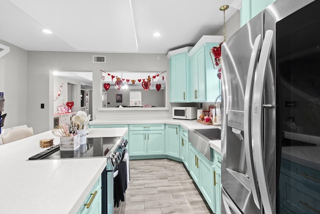 kitchen with stainless steel appliances, sink, pendant lighting, and light wood-type flooring