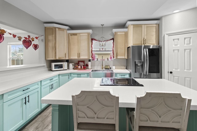 kitchen with a kitchen island, light brown cabinets, sink, hanging light fixtures, and stainless steel fridge