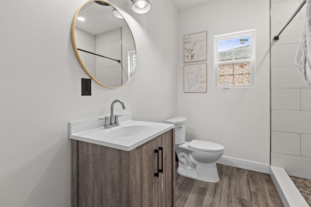 bathroom with hardwood / wood-style flooring, a shower, toilet, and vanity