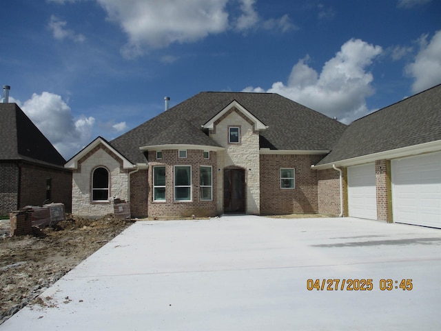 9250 Bellflower St, Beaumont, TX 77713 - french country style house with a shingled roof, a garage, stone siding, brick siding, and concrete driveway