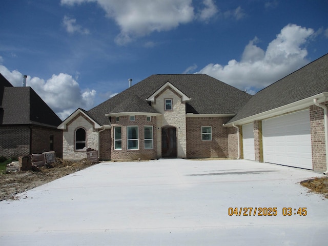 9250 Bellflower St, Beaumont, TX 77713 - french country home with a garage, brick siding, driveway, and roof with shingles