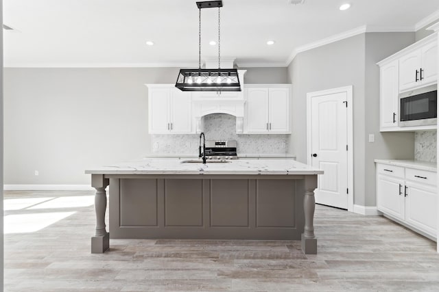 kitchen featuring a center island with sink, white cabinetry, stainless steel appliances, and light stone counters