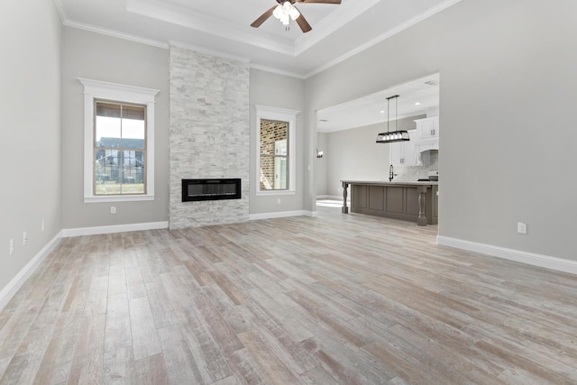 unfurnished living room with ceiling fan, a fireplace, crown molding, and light hardwood / wood-style floors