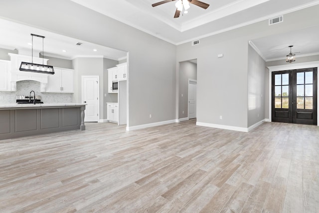 unfurnished living room with ceiling fan, sink, french doors, light hardwood / wood-style floors, and ornamental molding