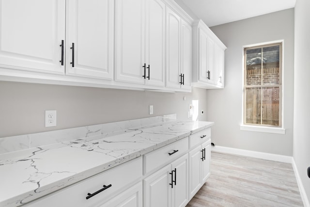 kitchen with white cabinets, light hardwood / wood-style floors, plenty of natural light, and light stone countertops