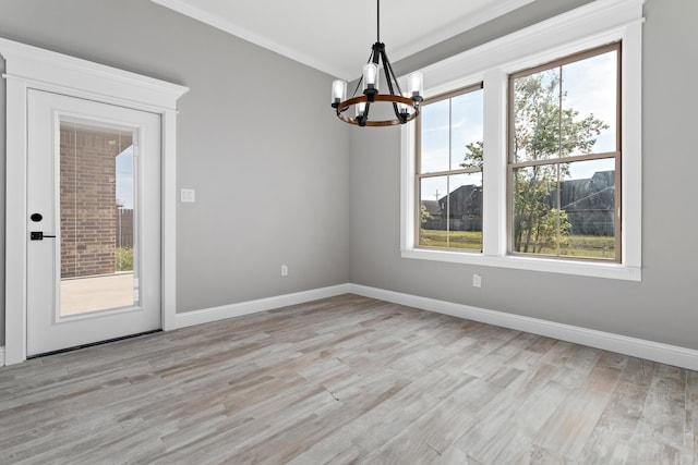 unfurnished dining area with ornamental molding, plenty of natural light, a chandelier, and light hardwood / wood-style floors