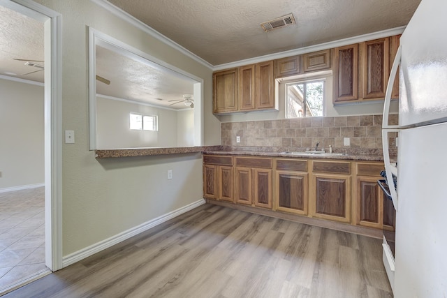 kitchen with tasteful backsplash, ornamental molding, a textured ceiling, sink, and white fridge