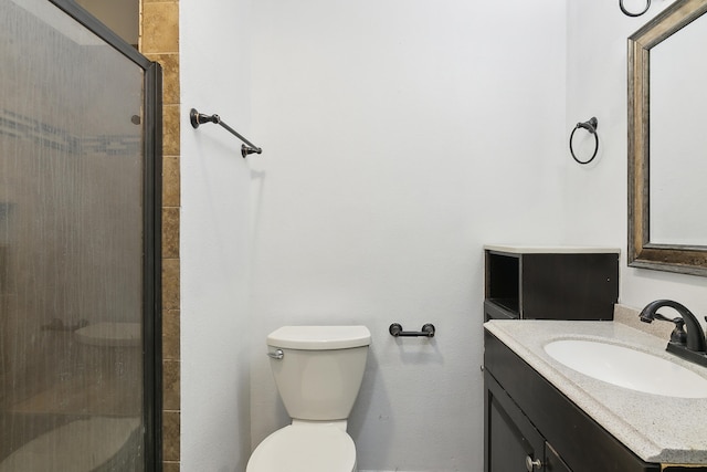 bathroom featuring vanity, a shower with shower door, and toilet