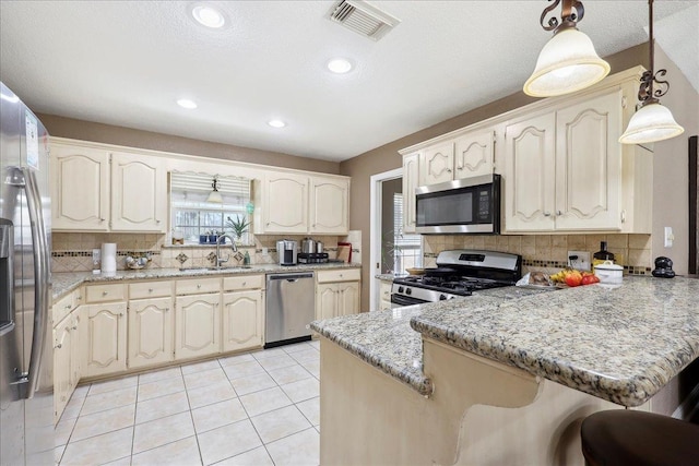 6006 Hazelwood Dr, Orange, TX 77632 - kitchen featuring sink, hanging light fixtures, light tile patterned floors, kitchen peninsula, and stainless steel appliances