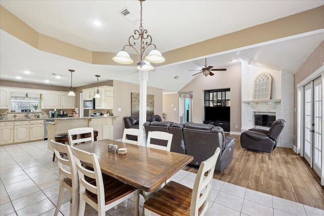 6006 Hazelwood Dr, Orange, TX 77632 - dining room with sink, vaulted ceiling, light tile patterned floors, ceiling fan, and a fireplace