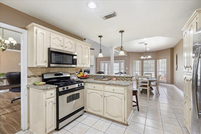 6006 Hazelwood Dr, Orange, TX 77632 - kitchen featuring pendant lighting, stainless steel appliances, light stone countertops, kitchen peninsula, and a chandelier