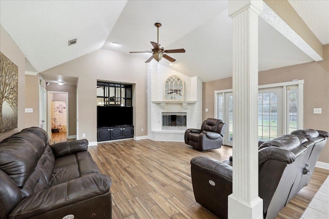 6006 Hazelwood Dr, Orange, TX 77632 - living room with lofted ceiling, a brick fireplace, light hardwood / wood-style flooring, ceiling fan, and decorative columns