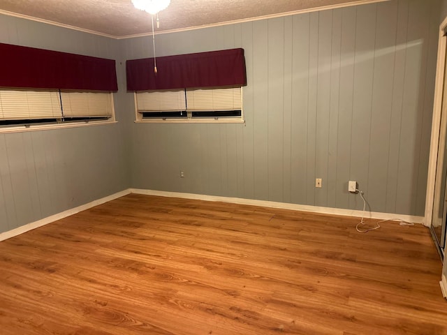 empty room featuring ornamental molding, a textured ceiling, and light wood-type flooring