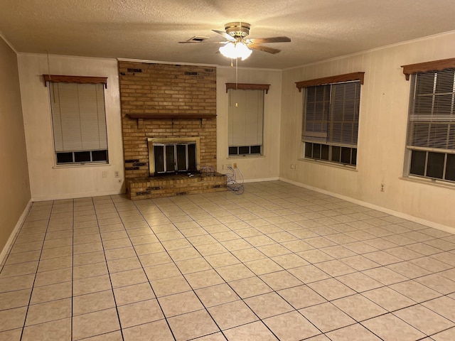 unfurnished living room featuring ceiling fan, a textured ceiling, a fireplace, light tile patterned flooring, and ornamental molding