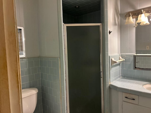 bathroom with vanity, toilet, and a shower with door