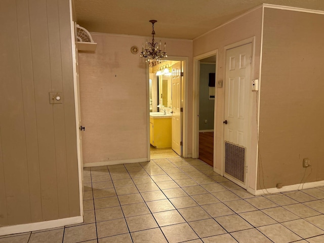 empty room featuring crown molding, light tile patterned floors, sink, and an inviting chandelier