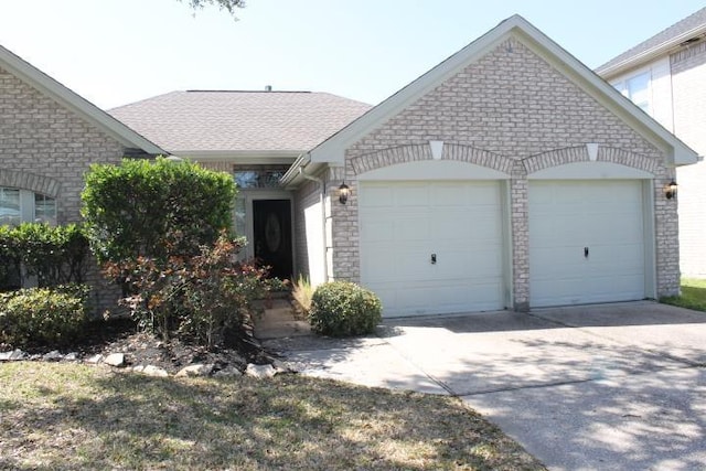 view of front of home featuring an attached garage, stone siding, and driveway