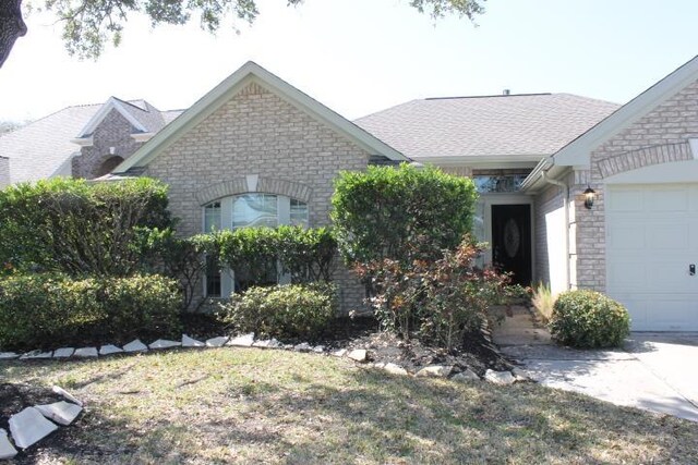 view of front of home with brick siding, stone siding, an attached garage, and a front lawn