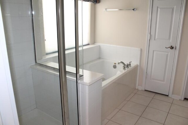 full bathroom featuring a garden tub, a stall shower, and tile patterned flooring