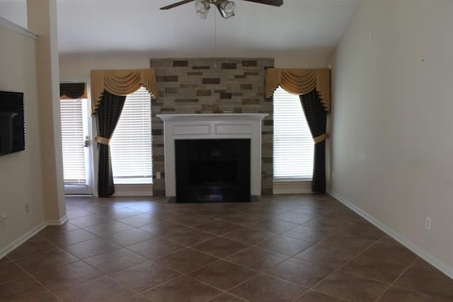 unfurnished living room with dark tile patterned floors, a fireplace, baseboards, and a ceiling fan