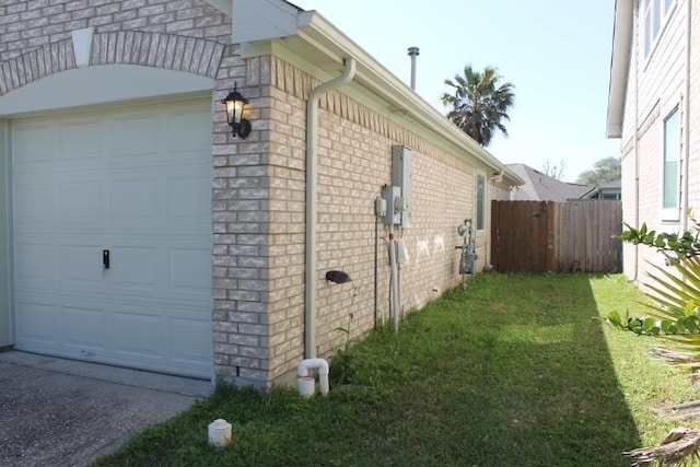 view of home's exterior featuring a garage, brick siding, a yard, and fence