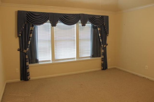 carpeted spare room featuring crown molding and baseboards