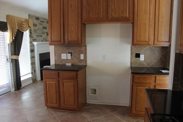 kitchen featuring dark countertops, light tile patterned floors, and brown cabinetry