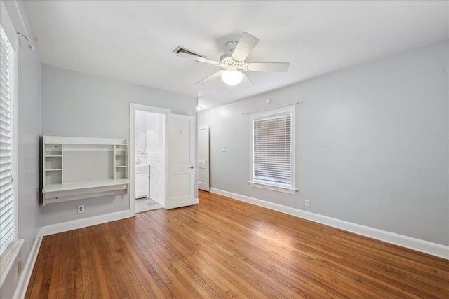 2342 Briarcliff Dr, Beaumont, TX 77706 - unfurnished bedroom with baseboards, wood finished floors, ceiling fan, connected bathroom, and multiple windows