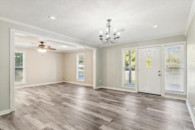 interior space featuring a wealth of natural light, ceiling fan with notable chandelier, hardwood / wood-style flooring, and ornamental molding