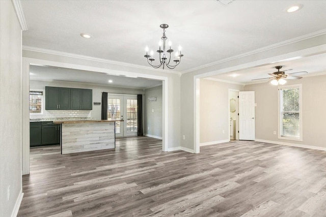 unfurnished living room with hardwood / wood-style flooring, ceiling fan with notable chandelier, crown molding, and french doors