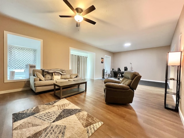 living room with baseboards, wood finished floors, and a ceiling fan