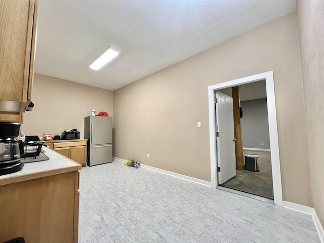 kitchen with baseboards, light countertops, and freestanding refrigerator