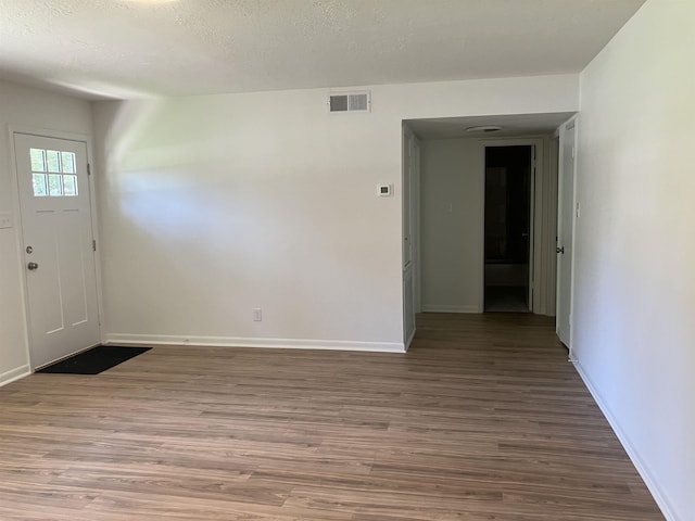 entryway with baseboards, visible vents, a textured ceiling, and wood finished floors