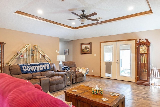 living room with a raised ceiling, ornamental molding, and french doors